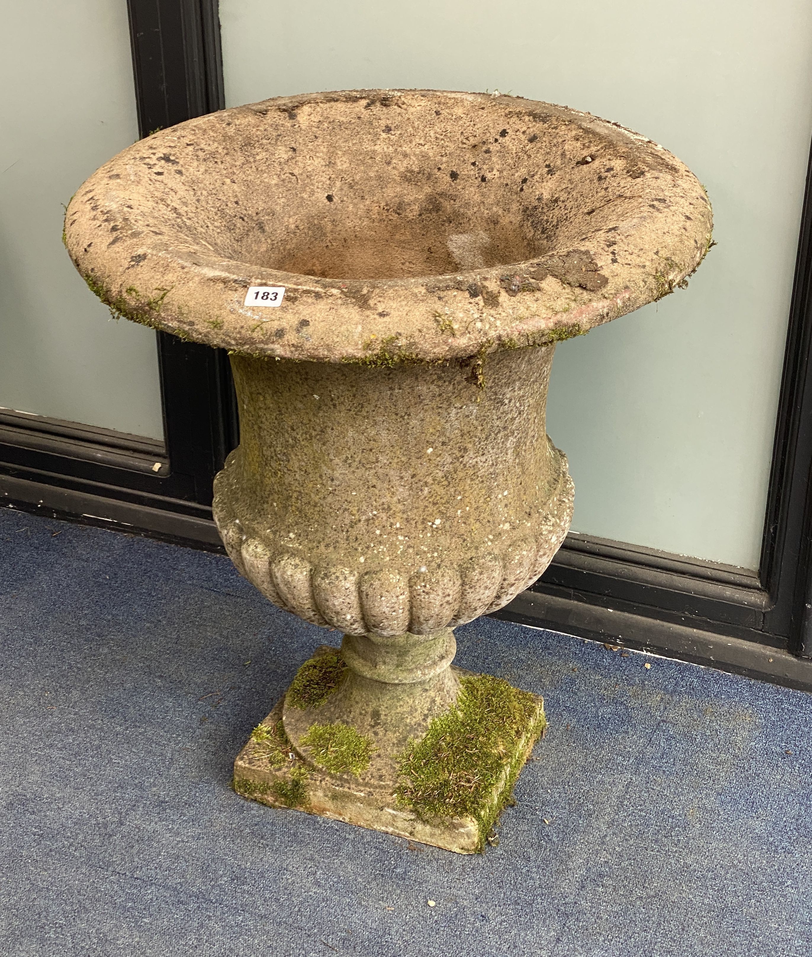 A reconstituted stone fluted campana shaped garden urn, diameter 62cm, height 70cm on square plinth